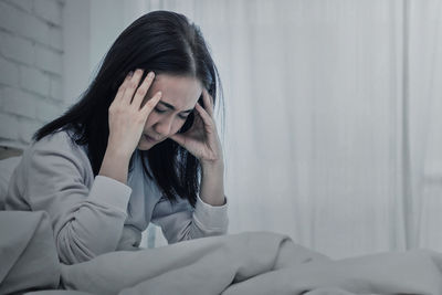 Young woman sitting on bed at home