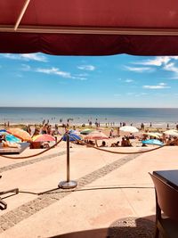 People at beach against blue sky during sunny day