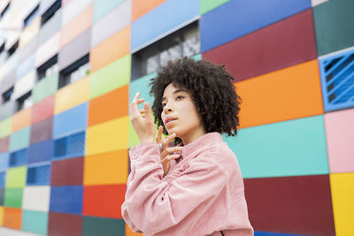 Young female dancer gesturing by colorful building