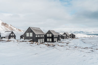 Houses on snow covered land against sky