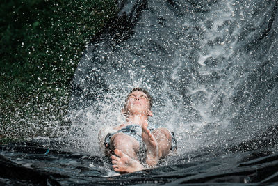 Portrait of shirtless man splashing water in sea