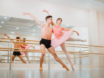 Full length of man and woman practicing ballet dance in studio