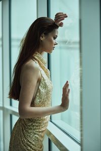 Young woman looking through window