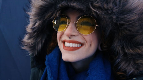 Close-up of smiling woman wearing sunglasses and fur coat