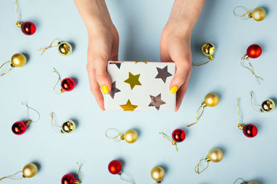 A woman holds a gift in her hands on blue background, new year concept