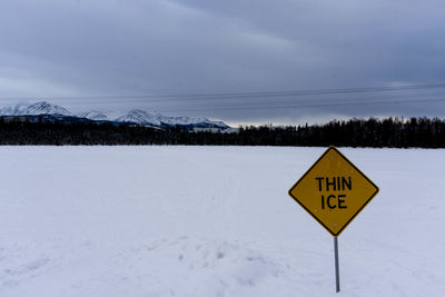 Road sign against sky during winter