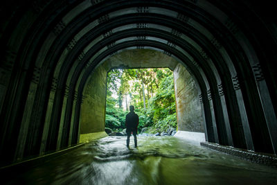 Rear view of silhouette man walking in tunnel