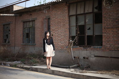 Young woman standing against brick wall