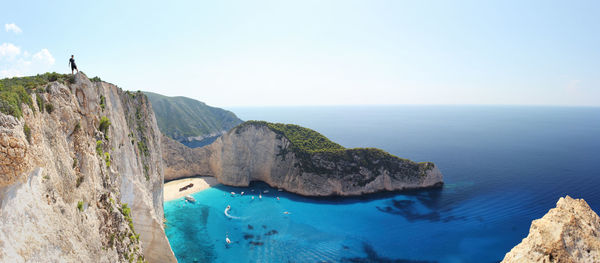 Scenic view of cliff by sea against clear sky