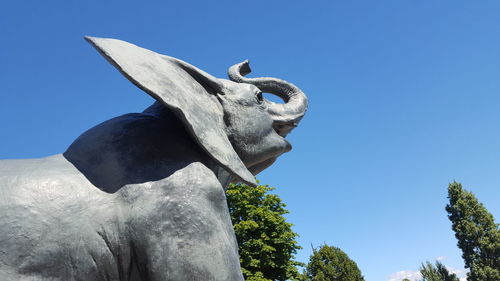 Low angle view of elephant sculpture against clear blue sky