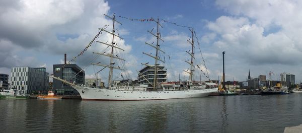 Boats moored at harbor against cloudy sky