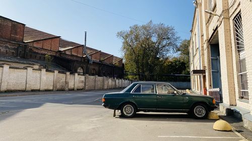 Cars on street by buildings against clear sky