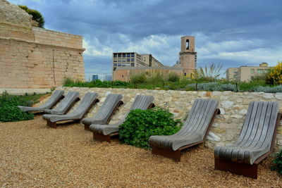 Empty chair on field against buildings