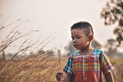 Boy standing on field against sky