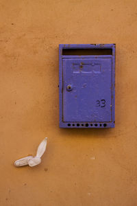 Handle by purple mailbox mounted on orange wall