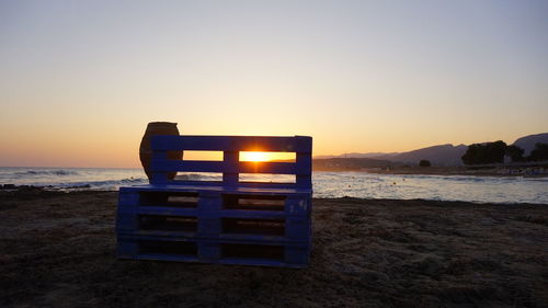 Lifeguard hut on beach against clear sky during sunset