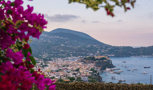 Scenic view of sea by townscape against sky