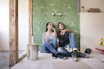 Couple renovating new house, sitting on ground planning bathroom