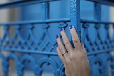 Cropped hand holding blue metal grate