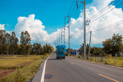 Road by trees against sky