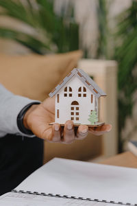 An african american man holds a miniature in his hands at home and takes notes