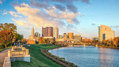 Scenic view of river by buildings against sky