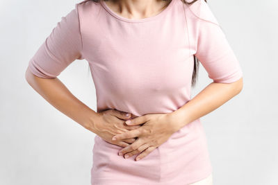 Midsection of woman touching hair against white background