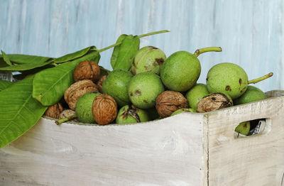 Close-up of fresh walnuts with leaf on table in white box with turquoise backgrund