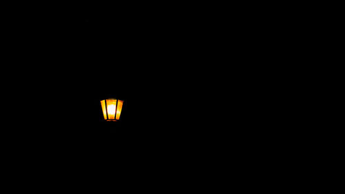 Low angle view of illuminated lamp against black background