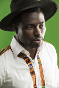 Man wearing black hat against green background