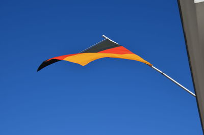 Low angle view of flag against clear blue sky