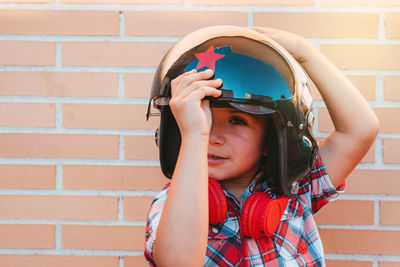 Portrait of boy with russian pilot's helmet on brick wall