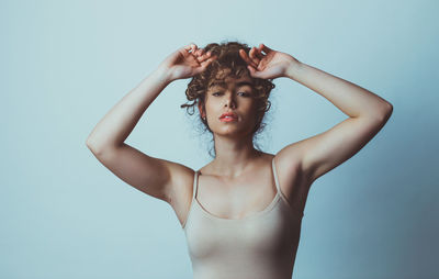 Portrait of young woman standing against colored background