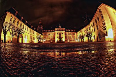 Illuminated building by street against sky at night