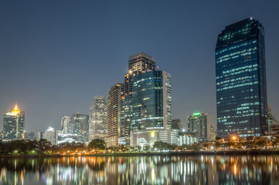 Illuminated buildings by city against sky at night