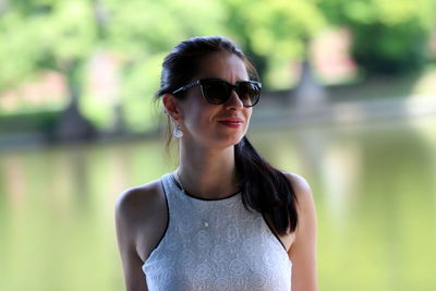 Young woman wearing sunglasses against lake