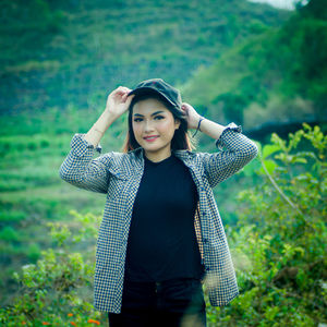 Portrait of beautiful young woman standing against plants