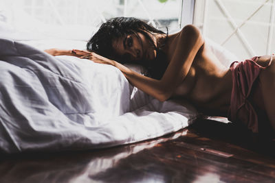Portrait of seductive woman lying on bed