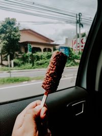 Midsection of person holding ice cream in car