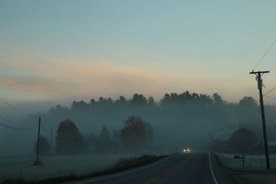 Road amidst trees against sky during sunset