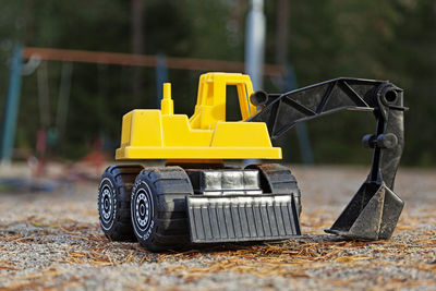 Yellow toy excavator in the sandbox