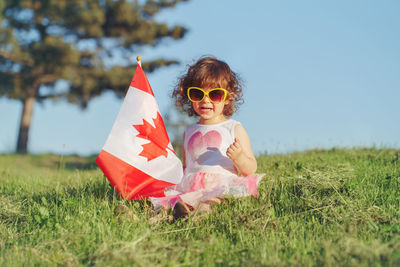 Girl with canadian flag sitting on land