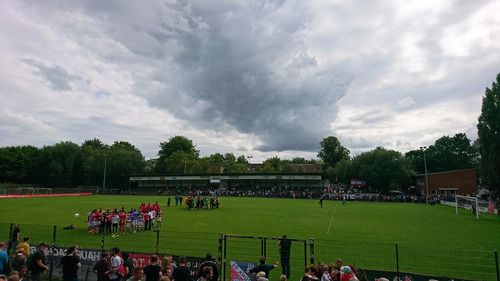 People playing soccer on field against sky