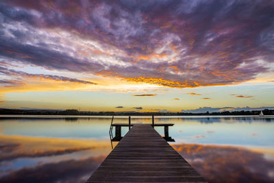 Pier over lake against sky during sunset