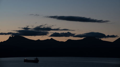 Silhouette mountain by sea against sky during sunset