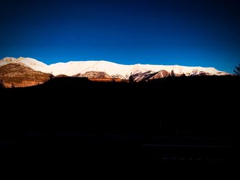 Scenic view of snowcapped mountains against clear blue sky