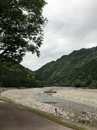 Scenic view of road by mountains against sky
