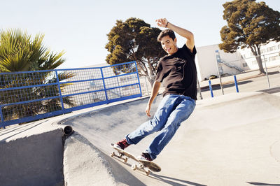 Man skateboarding on sports ramp in park against clear sky