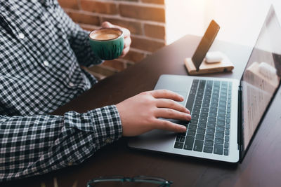 Man working at the laptop with a cup of coffee at home. blurred background