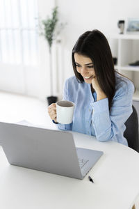 Woman using phone while sitting on table